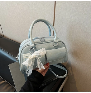 Close-up of light blue bowling bag with lace bow pendant and silver hardware detail