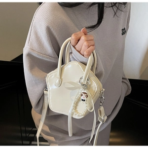 Detail of cream star-shaped mini handbag featuring bow, pearl pendant and cartoon charm