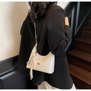 Model wearing a cream wax leather crossbody bag with COIN logo and a decorative silk scarf
