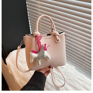 Detail of light pink bucket bag with lychee texture and flying horse charm attachment