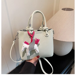 Detail of cream white pebbled leather bucket bag with a pegasus charm and knotted handle