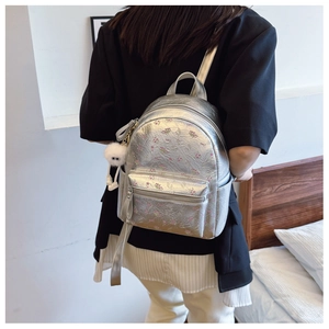 Détail du sac à dos argenté à fleurs avec breloque en peluche et compartiments