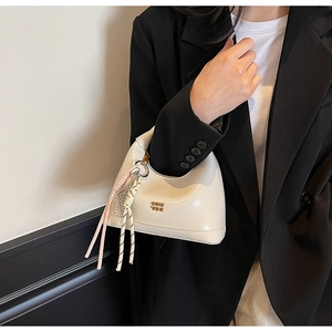Detail of off-white patent leather dumpling bag with gold COIN logo and woven knot charm