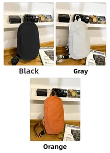 Three colors of waterproof crossbody travel bags in black, grey, and orange on a wooden desk