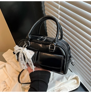 Detail of glossy black patent bowling bag with elegant white lace pearl bow charm