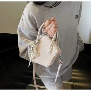 Detail of light pink star-shaped mini crossbody bag with pearl charm and ribbon