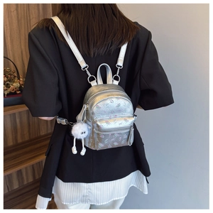 Mini sac à dos argenté à fleurs avec porte-clé en peluche porté par un mannequin