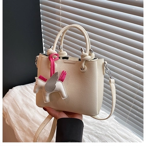 Detail of cream white litchi pattern bucket bag with a cute horse leather charm