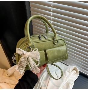 Detail of green Boston bag with matte PU leather, twin pockets, lace bow and pearl charm