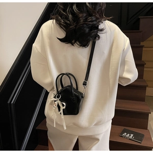 Detail of black mini star shaped crossbody bag with pearl charms and white ribbon