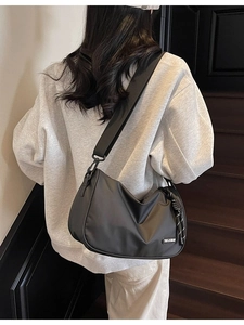 Minimalist black nylon crossbody dumpling bag with wide shoulder strap for casual style