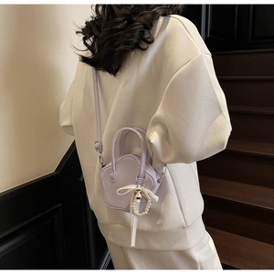 Detail of star-shaped purple mini crossbody bag with pearl ribbon pendant on a model