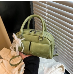 Close-up of sage green bowling bag with lace pearl bow and silver hardware detail