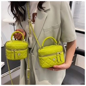 Detail of neon green quilted mini box bag with chain strap and camellia zip puller