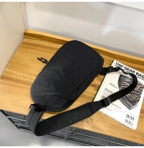 Detail of adjustable shoulder strap with plastic buckle on a black nylon crossbody bag