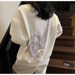 Detail of star-shaped lavender crossbody bag with pearl charm on a model