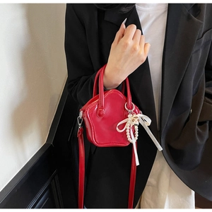 Detail of red star-shaped patent leather bag with pearls and ribbon on model coat