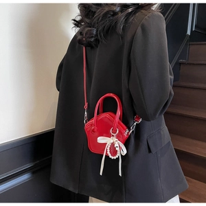 Close-up of red star-shaped mini crossbody bag with pearl charms and white silk bow