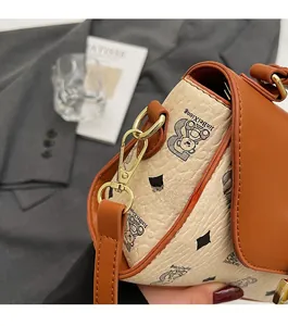 Detail of vintage crossbody bag with bear pattern print and gold hardware accents