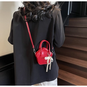Detail of red star-shaped mini handbag with pearl charm and white satin bow accent