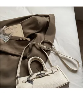 Detail of white litchi pattern leather handbag with metal heart charm and golden lock