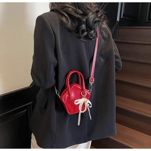 Red shiny star-shaped mini bag with bow and pearl detail worn over a black blazer
