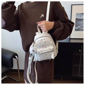 Détail d'un mini sac à dos blanc à motifs floraux roses avec un pendentif en peluche