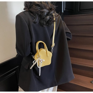 Detail of yellow star-shaped crossbody bag with pearl ribbon and black suit matching