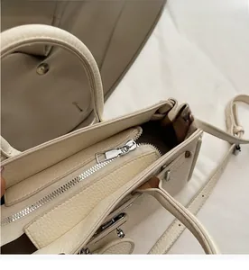 Close-up of smooth silver zipper and premium lychee texture on beige handbag
