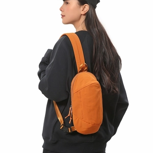 Detail of water-resistant orange crossbody bag showing nylon texture and adjustable strap