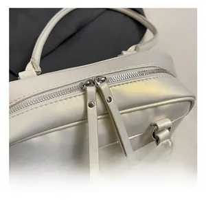 Details der silbernen Doppel-Reißverschlüsse und Metallbeschläge an weißer Ledertasche