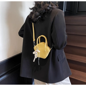 Detail of star-shaped yellow mini crossbody bag with cute charm and pearl strap