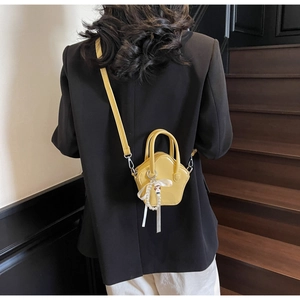 Model wearing yellow star-shaped mini crossbody bag with pearl charms and cartoon pendant