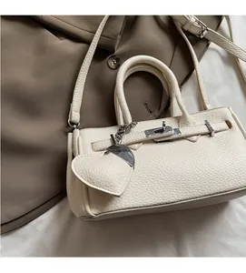 Close-up of cream white lychee leather texture and metallic turn-lock on the handbag
