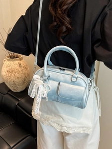 Blue metallic bowling handbag with pearl bow pendant shown by a model for scale
