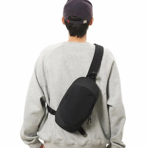 Rear view of a black lightweight crossbody bag on model with adjustable strap detail