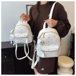 Détail de deux mini sacs à dos blancs à fleurs montrant la comparaison des tailles