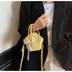 Macro shot of yellow star-shaped mini bag with pearl charm and smooth faux leather finish