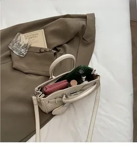 Detail of cream lychee leather handbag showing spacious interior and metal hardware