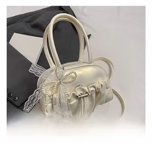 Detail of ruched Boston bag with pearl lace bow and adjustable shoulder strap