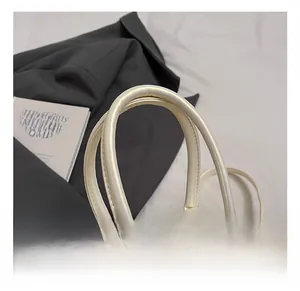 Detailed close-up of pearl white pleated bag handle with decorative pearls and lace charms