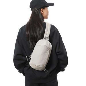 Close-up of lightweight light gray crossbody bag with adjustable wide strap on model