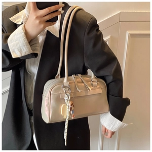 Detailansicht der cremefarbenen Boston-Tasche mit Metallreißverschluss und Anhänger