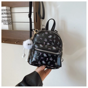 Détail du mini sac à dos noir à fleurs et nœuds roses avec un pendentif peluche blanc