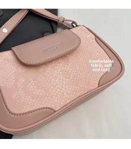 Detail of pink faux crocodile leather shoulder bag with silver logo and stitching