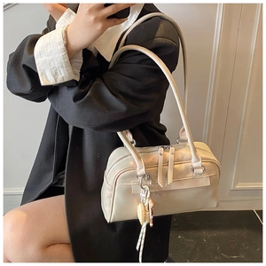 Detail der cremeweißen glänzenden Boston Bag mit Doppelreißverschluss und Anhänger