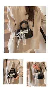 Detail of matte leather mini Boston bag featuring embossed texture and white lace bow