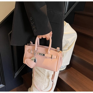 Detailed view of pink lychee leather handbag with silver lock and heart pendant