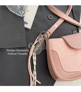 Detail of pink faux leather bag with snake texture and creative metal charms decoration