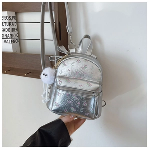 Détail du mini sac à dos argenté à motif floral avec charme en boule de peluche